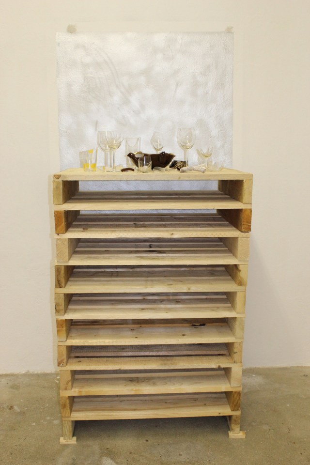 © Renate Egger. Zerbrochene Erinnerungen/Broken memories, 2012. Installation, Fotografie. Gläser, Porzellan, römisches antikes Fragment, Muschel aus Zanzibar auf Holzpaletten/Installation, photography. Glasses, porcelain, roman antique fragment, shell from Zanzibar on wooden pallets